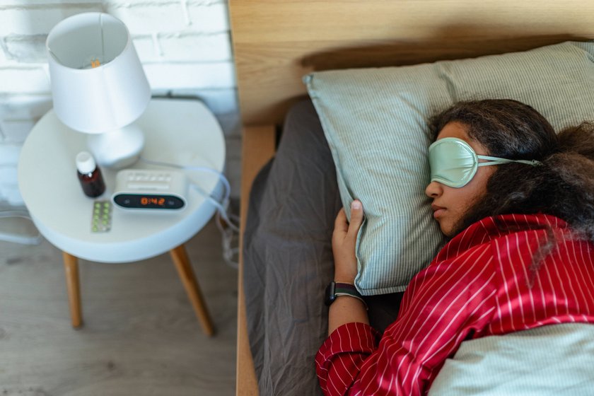 Frau schläft mit Schlafmaske im Bett
