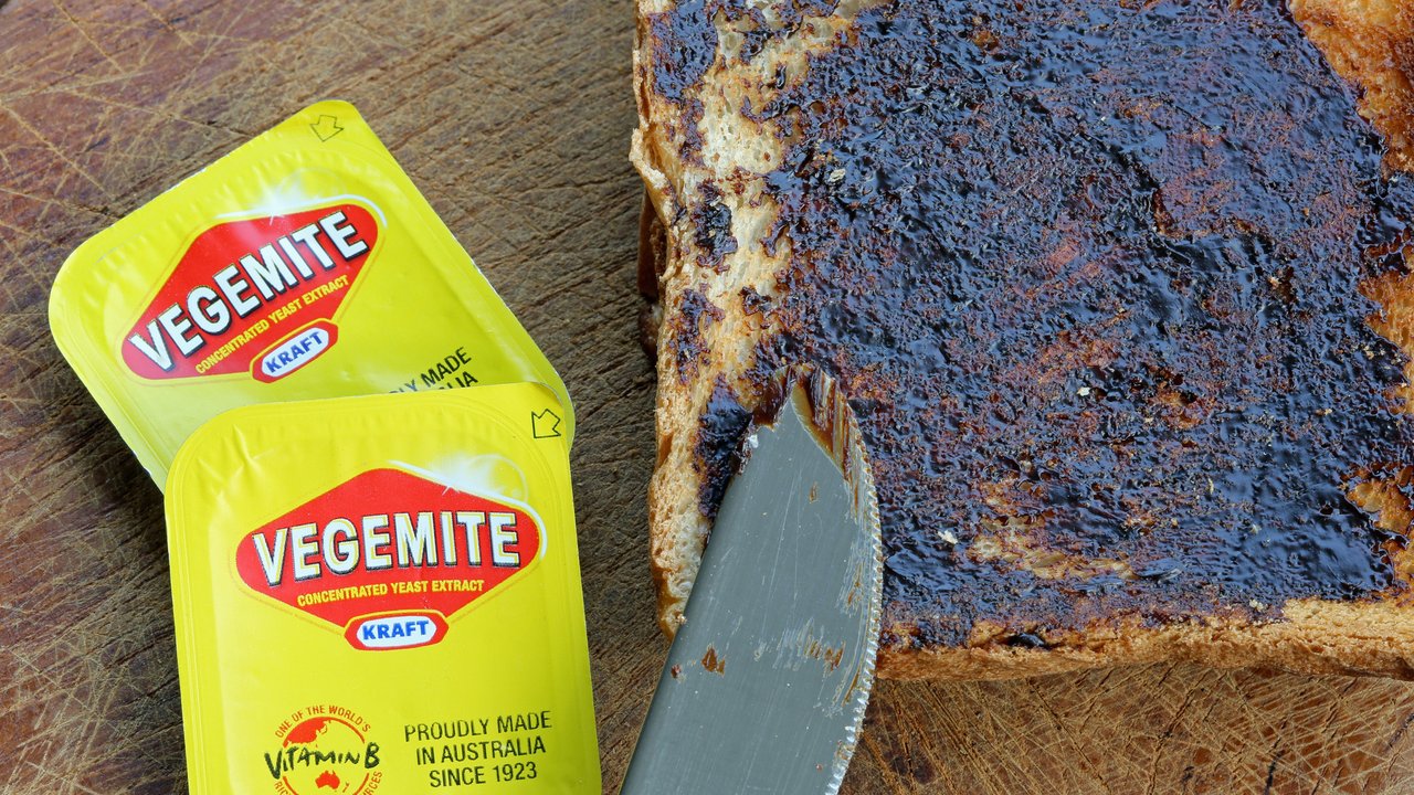 Reichenbach, Germany - 0ctober 4, 2013: Vegemite on Toast - Produce in Australia at Kraft Foods' Port Melbourne. It's a popular dark brown australian Food Paste - used as spread for sandwiches and toast - the Australian People love it for Breakfast. It taste similar to beef bouillon. I shot this photo at home in Germany - the Vegemite was a Souvenir from my Australia Trip. Toast with Knife and 2 small packages of Vegemite.