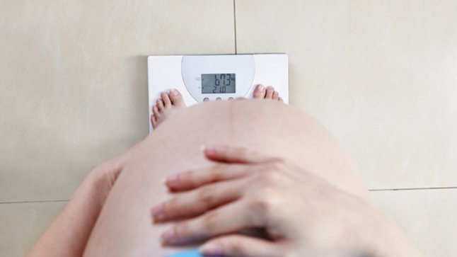 Abnehmen in der Schwangerschaft: Schwangere Frau auf Waage.