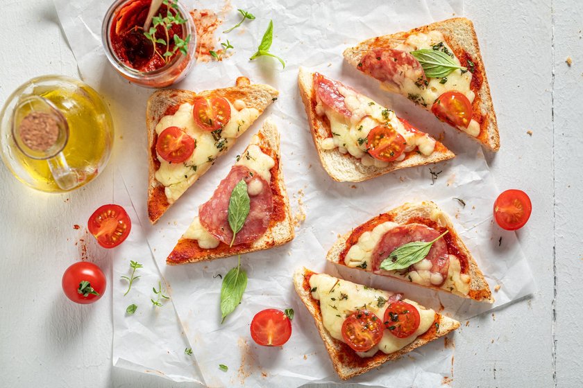 Unhealthy Toast with cheese, salami and basil on white paper