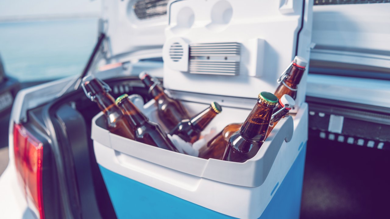 close up view of portable fridge with beer standing in car