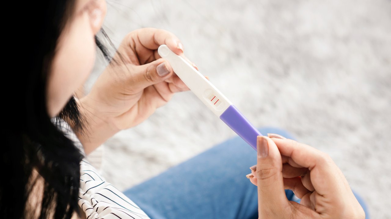 closeup Asian woman hand holding  pregnancy test showing positive result
