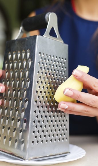 Young woman grating ginger in the kitchen Young woman grating ginger in the kitchen
