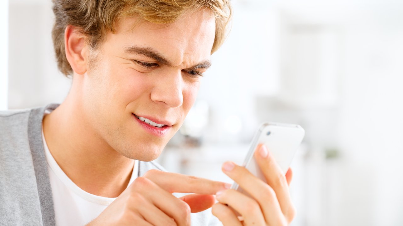 Frustrated man sending text message using mobile phone at home