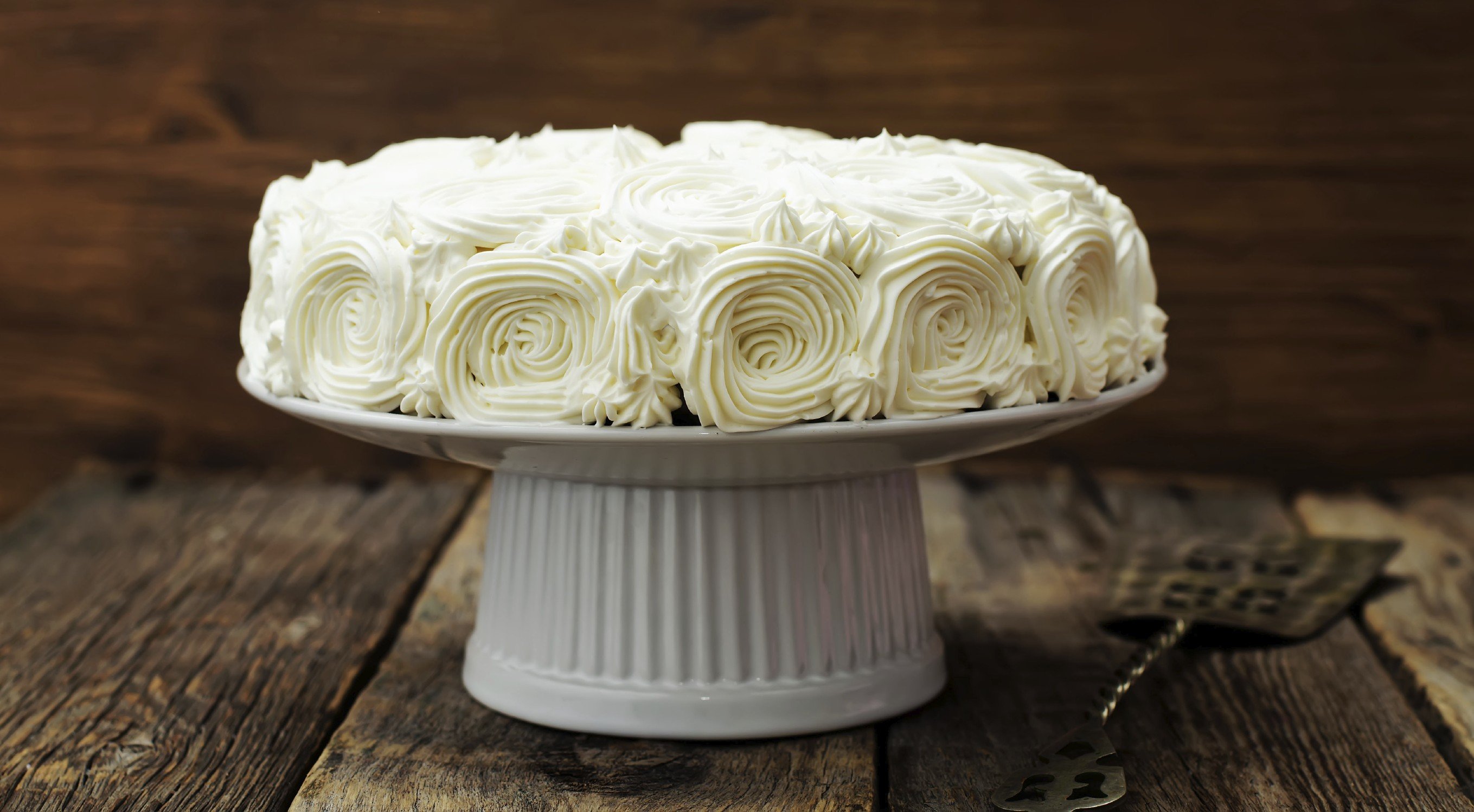 cake with vanilla cream in the form of roses on a dark wood background. tinting. selective focus cake with vanilla cream in the form of roses on a dark wood background. tinting. selective focus
