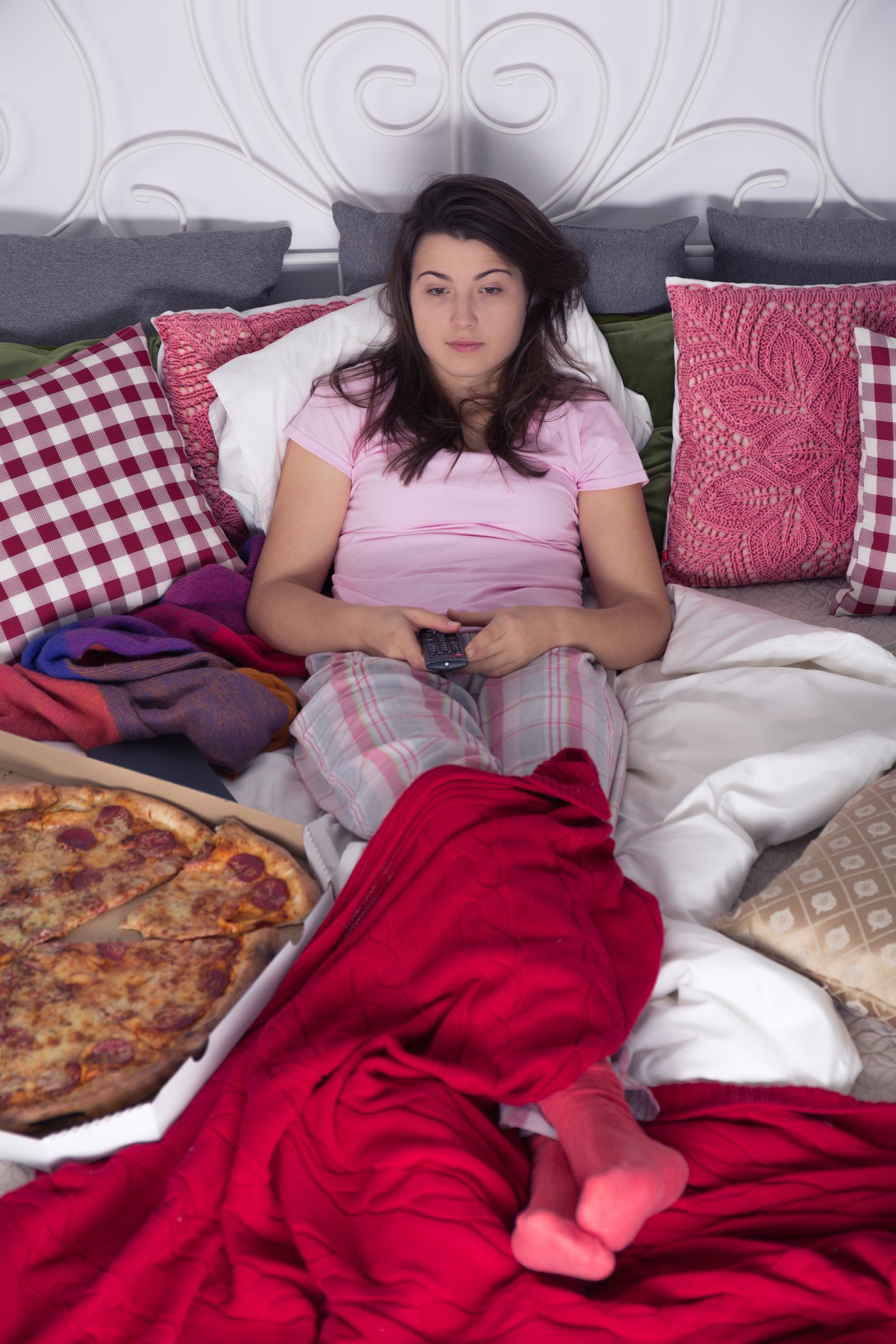 Frau isst Pizza im Bett