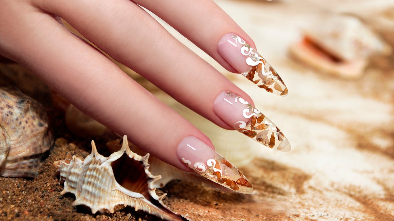 Nail design with brown and white these little shells inside gel nails on the background of shells and sand