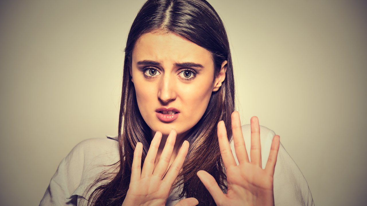 Closeup portrait of scared woman raising hands up in defense afraid about to be attacked or avoiding unpleasant situation, isolated on gray background. Negative human emotion facial expression feeling