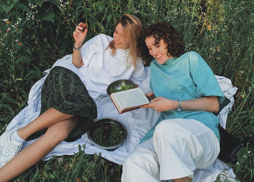 zwei Frauen, die auf einer Decke im Gras liegen