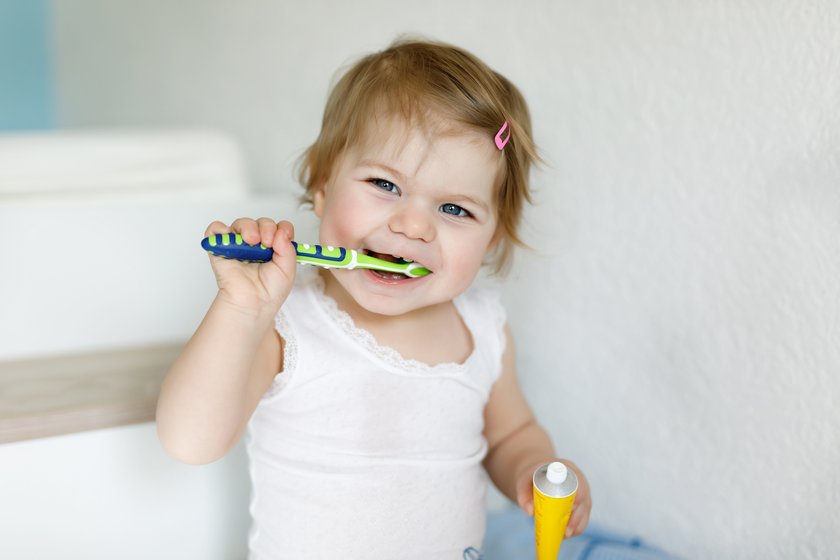 Kleines Mädchen putzt sich die Zähne und lacht dabei