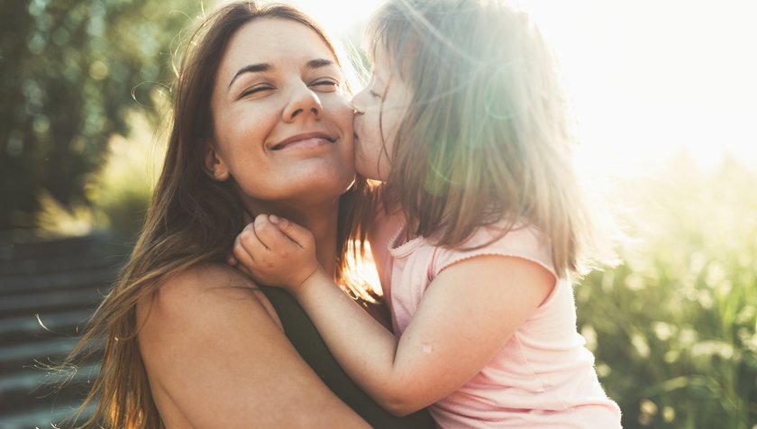 Kind küsst Mama auf die Wange