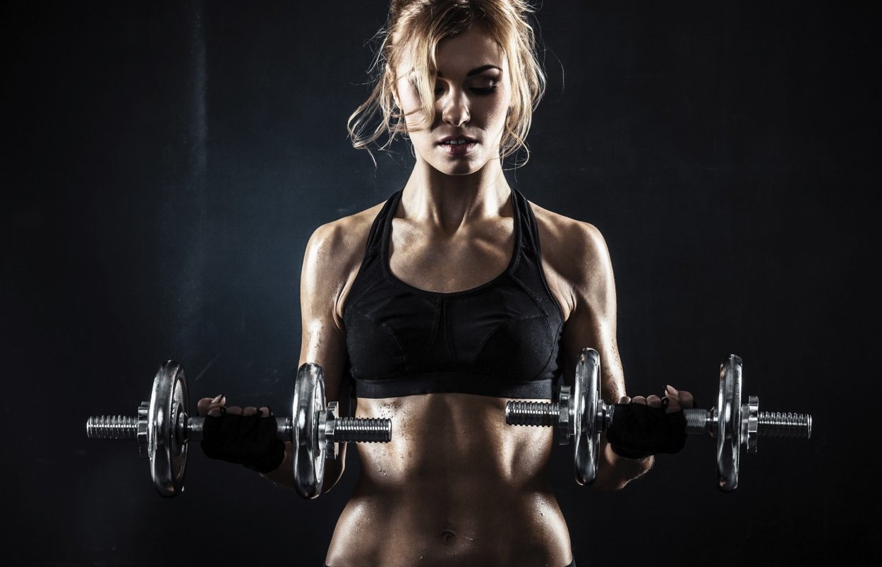 Brutal athletic woman pumping up muscules with dumbbells Brutal athletic woman pumping up muscules with dumbbells