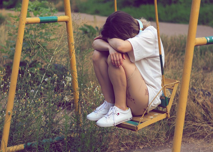 junge Frau, die traurig auf Schaukel sitzt