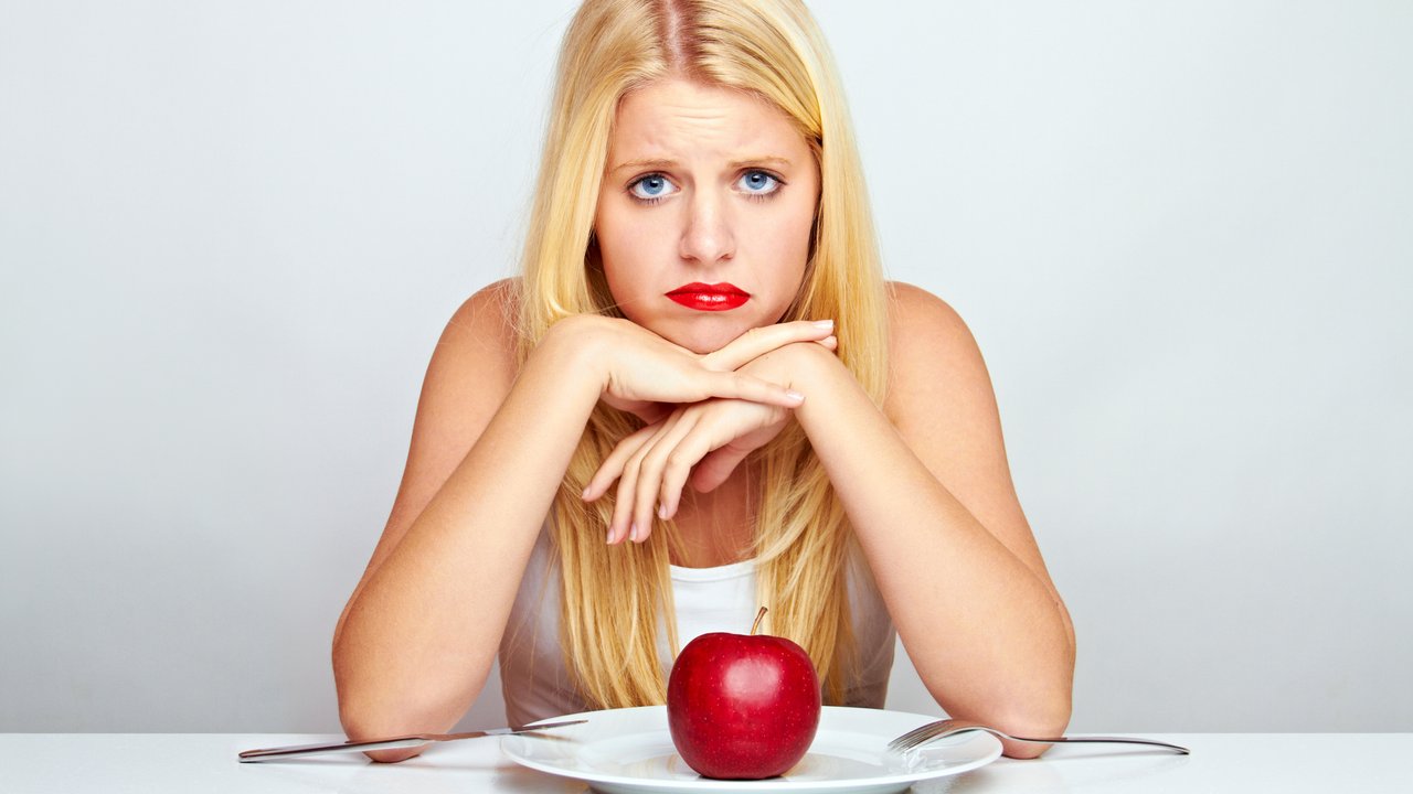 young blond woman with red apple on a plate with silverware