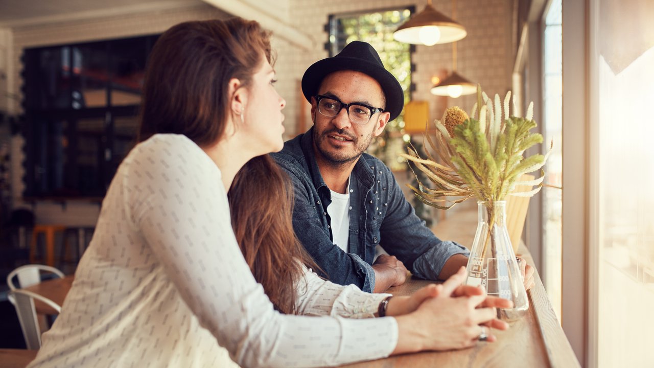Portrait of young man and woman sitting at a cafe and talking. Young couple relaxing in a coffee shop.