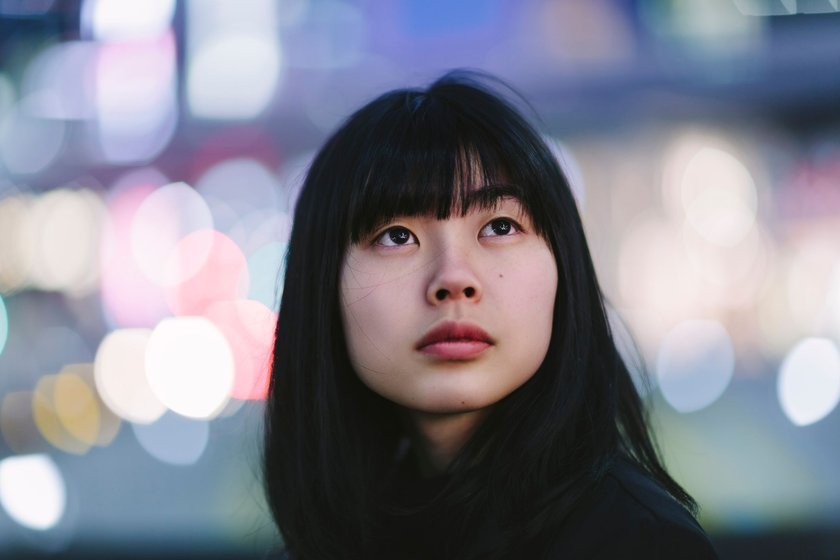 Porträt einer jungen Frau, die nachts in einer Stadt unterwegs ist