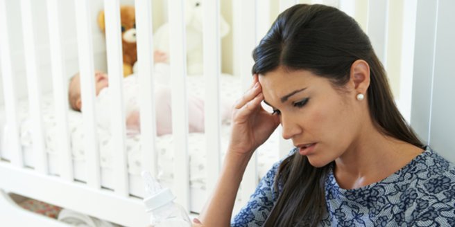 Wochenbettdepression: Traurige Mutter vor Babybett Wochenbettdepression: Traurige Mutter vor Babybett