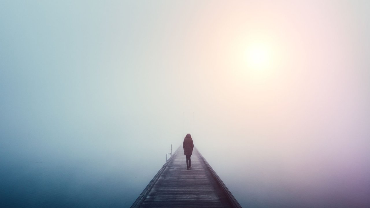 Eine Frau läuft allein über eine Brücke im Nebel