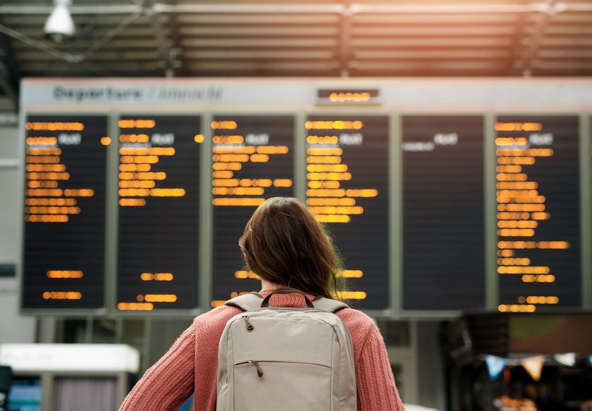 frau am flughafen vor fluganzeige