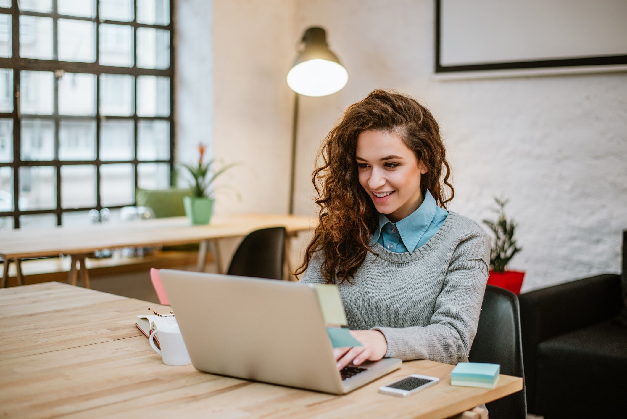Frau sitzt am Schreibtisch und arbeitet auf ihrem Laptop Frau sitzt am Schreibtisch und arbeitet auf ihrem Laptop
