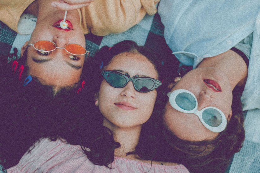 Drei Frauen liegen nebeneinander auf einer Decke