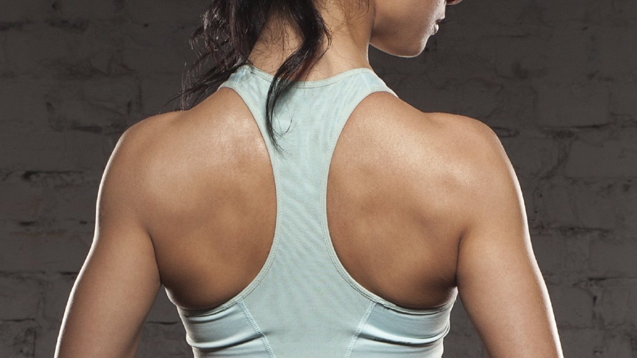 the back of sports women on training, fitness girl with muscular body, do her workout