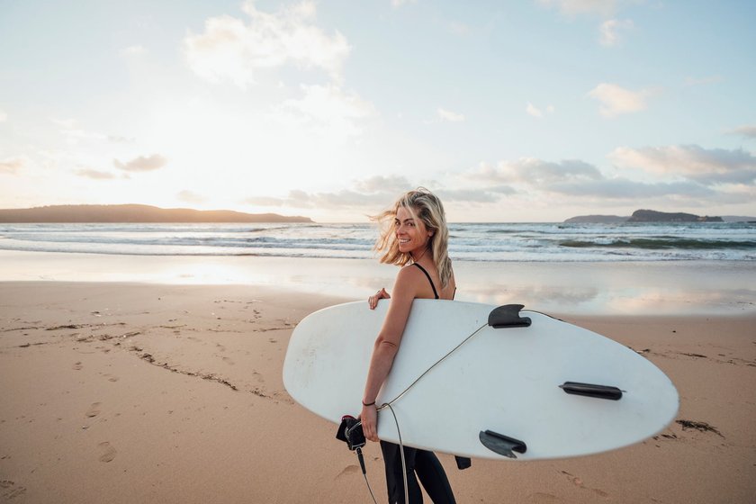 Frau mit Surfbrett am Strand