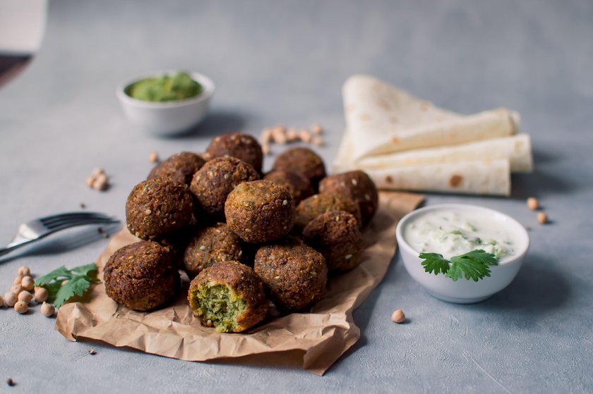 Fresh falafel balls on a black gray background with yoghurt sauce. Vegetarian food, diet, proper nutrition.