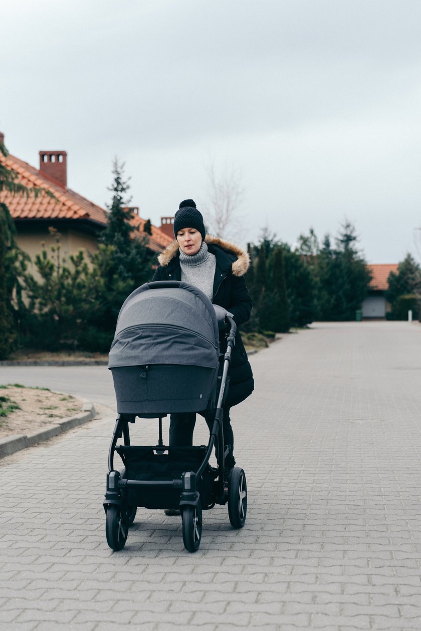 Frau spaziert mit ihrem Baby im Kinderwagen