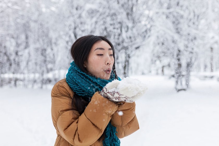 Frau mit Schnee in den Händen im Winter